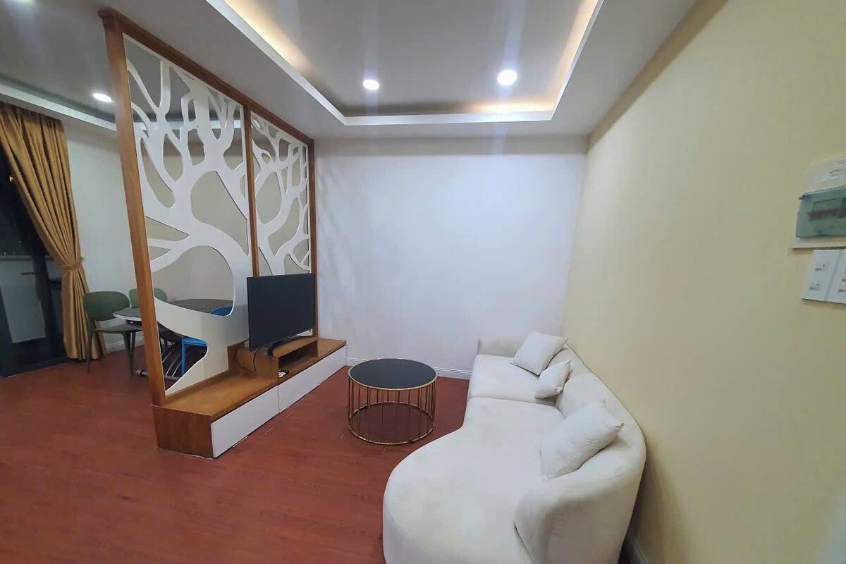 A modern living room with a white sectional sofa, a round coffee table, and a TV on a wooden stand.