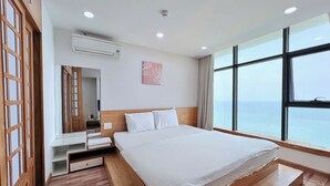 Ein Hotelzimmer mit einem großen Bett, Holzboden, Meerblick und modernem Design.