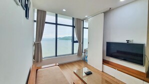 Ein modernes Wohnzimmer mit großem Fenster, Flachbildfernseher und Glastisch.