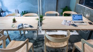 A modern office space with wooden tables and chairs, a laptop, and a glass of water on one table. - Shao Guang 188 (Yuchi)