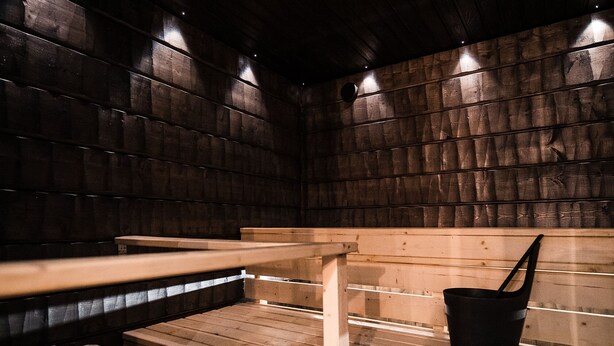 Eine Sauna mit Holzbänken und einem schwarzen Eimer.