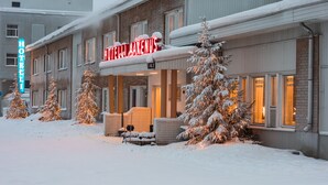 Ein Hotel mit verschneiter Fassade und beleuchteter Beschilderung.