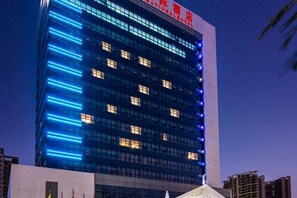 A high-rise building with illuminated blue lines on its facade, likely indicating a hotel or commercial property. - Vienna International Qianhai Branch (Shenzhen)