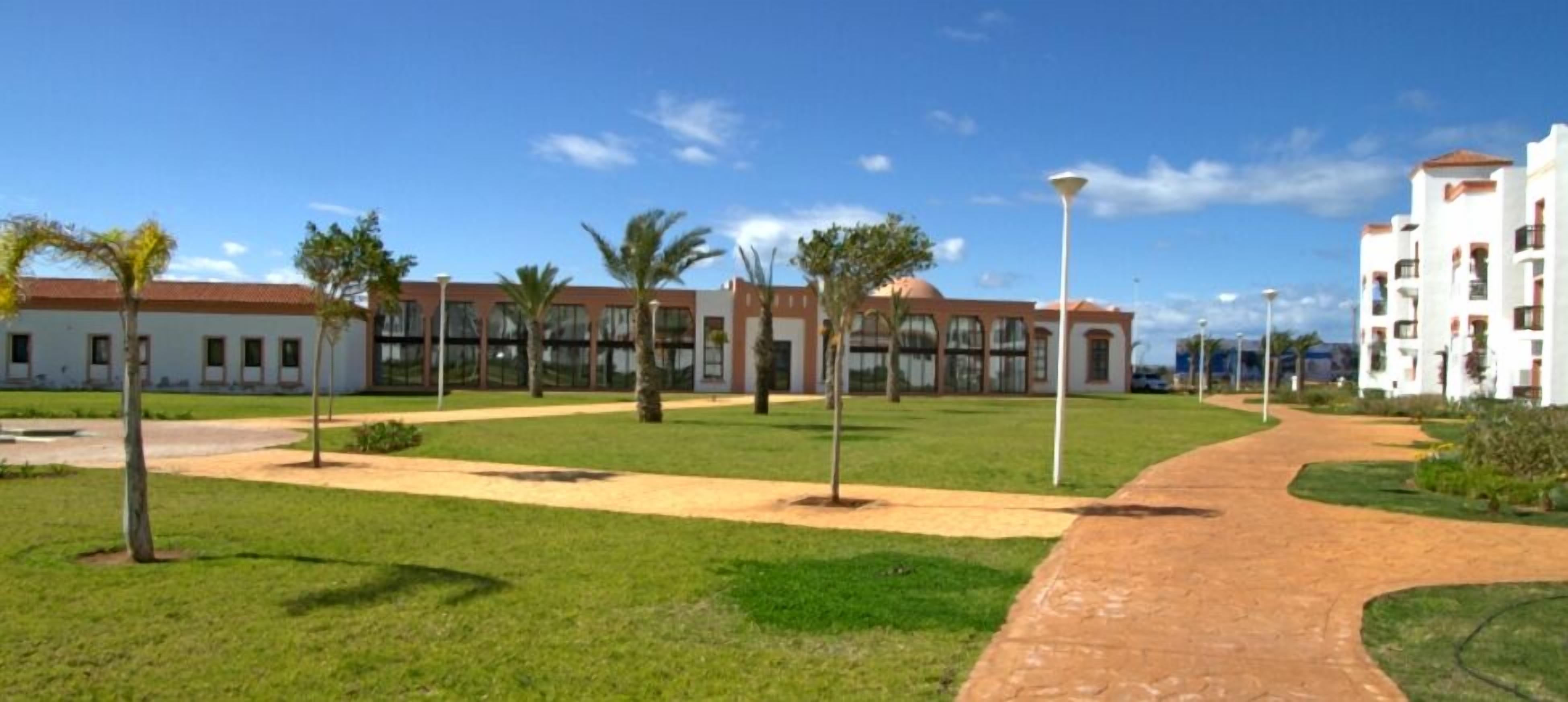 A pathway leading to a building with multiple windows and a red roof.