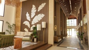 A spacious lobby with a high ceiling, a large decorative wall, and a seating area with a sofa and chairs. - Aureo La Union (San Fernando)