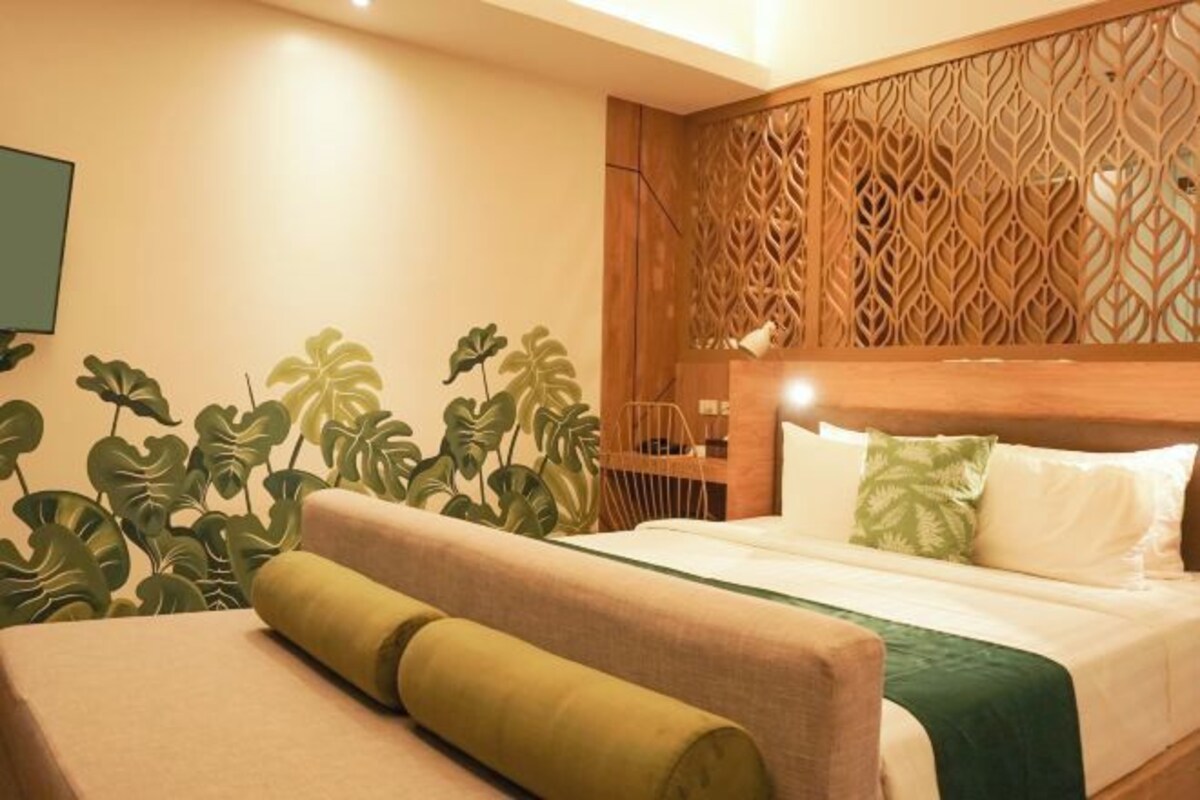 A hotel room with a bed, a wooden headboard, and a decorative panel.