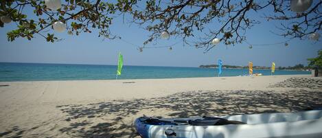 Una spiaggia con un kayak e una tavola da paddleboard, acqua cristallina e un mare calmo.
