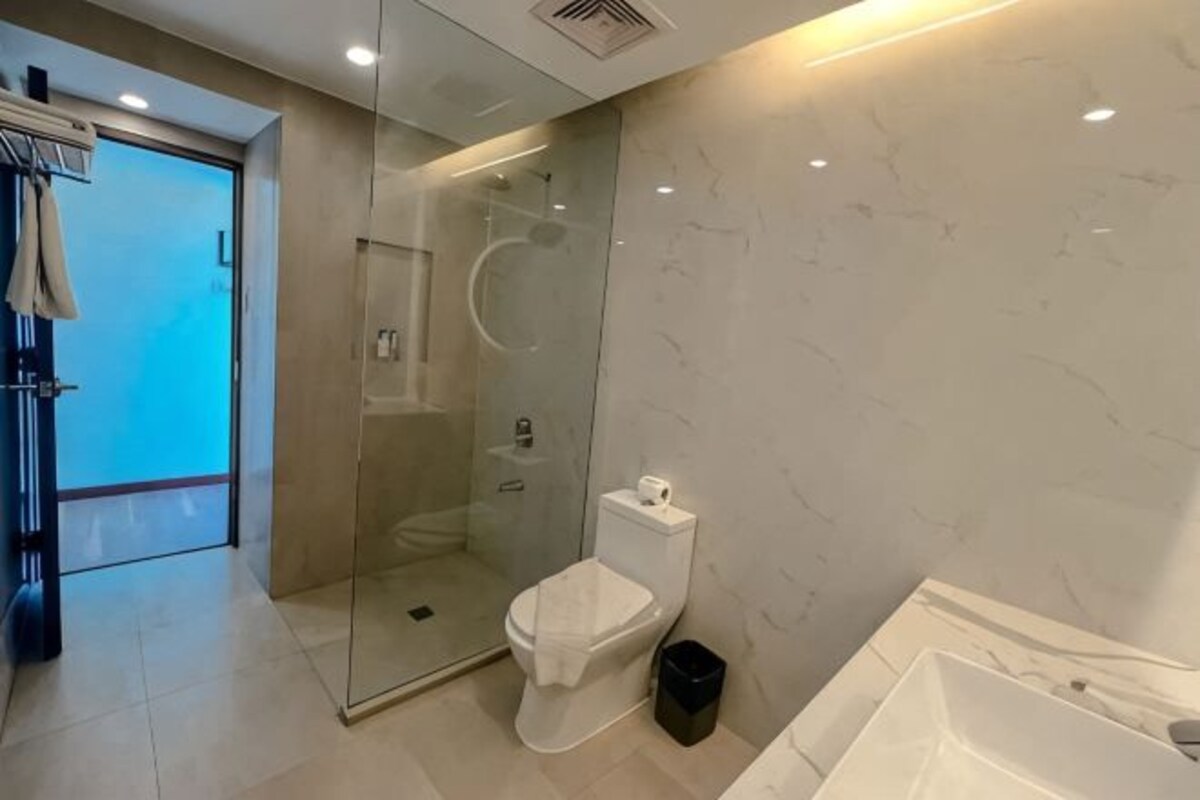 A modern bathroom with a glass-enclosed shower, a toilet, and a bathtub.