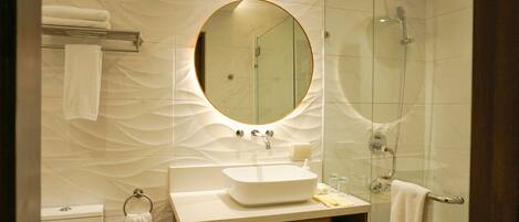 Un baño moderno con un espejo redondo, un lavamanos y una ducha.