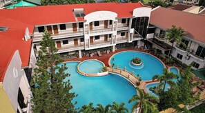 A hotel with multiple balconies, a central swimming pool, and surrounding greenery. - Seorabeol Grand Leisure Hotel (Olongapo)
