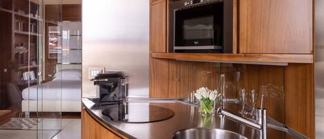 A modern kitchen with a built-in oven, a stainless steel sink, and wooden cabinetry.