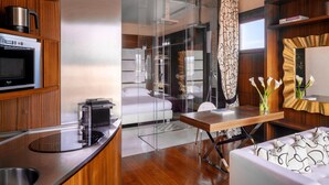 A modern hotel room with a kitchen area, a dining table, and a sofa. - Repubblica Firenze Luxury Apartments | UNA ESPERIENZE (Florence)