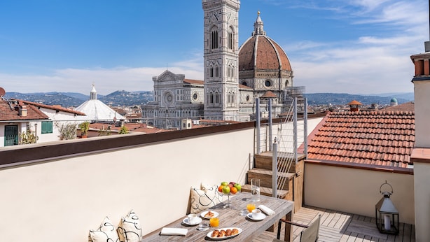A terrace with a table set for breakfast, overlooking a historic building with a dome and bell tower. - Repubblica Firenze Luxury Apartments | UNA ESPERIENZE (Florence)