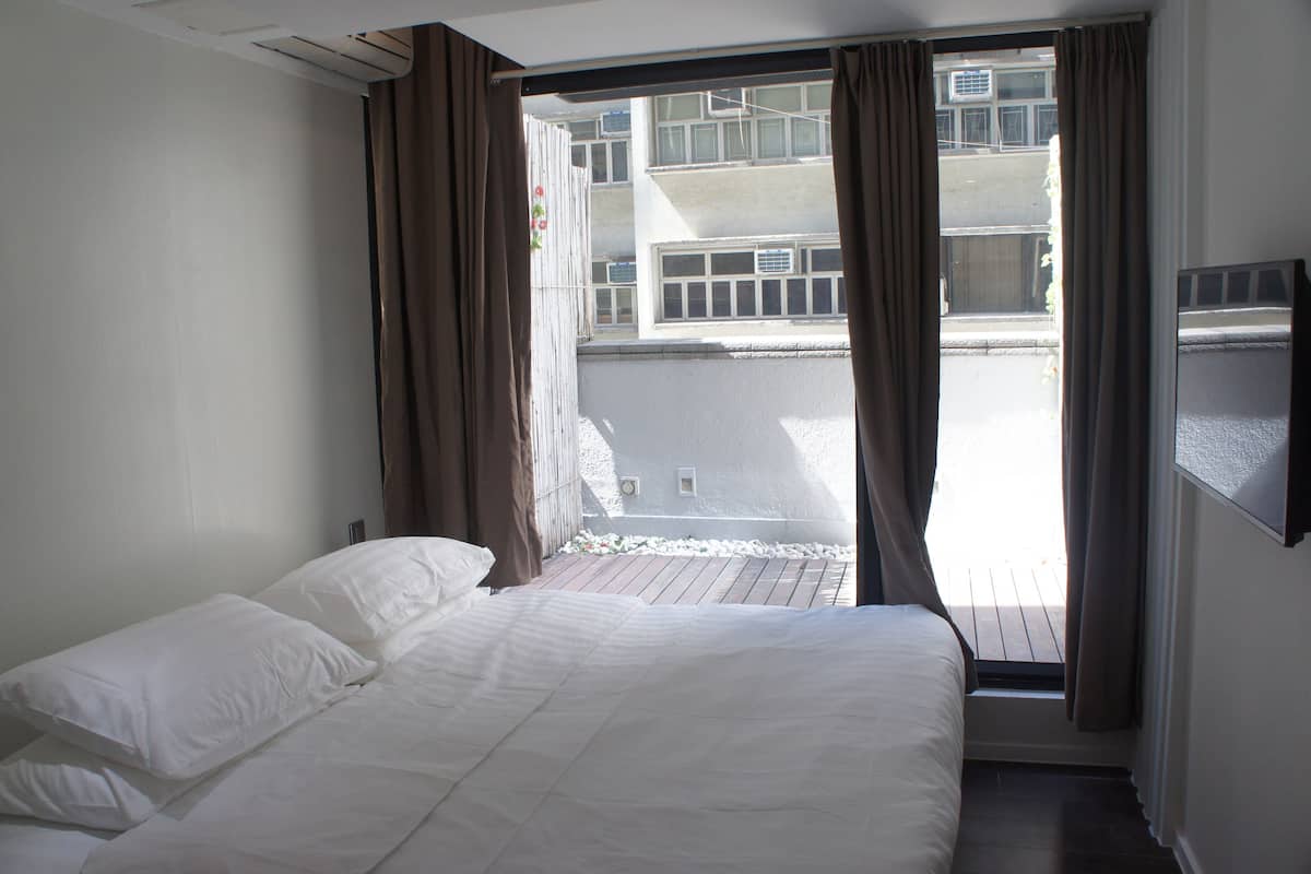 A hotel room with a bed, curtains, and a view of the building outside.