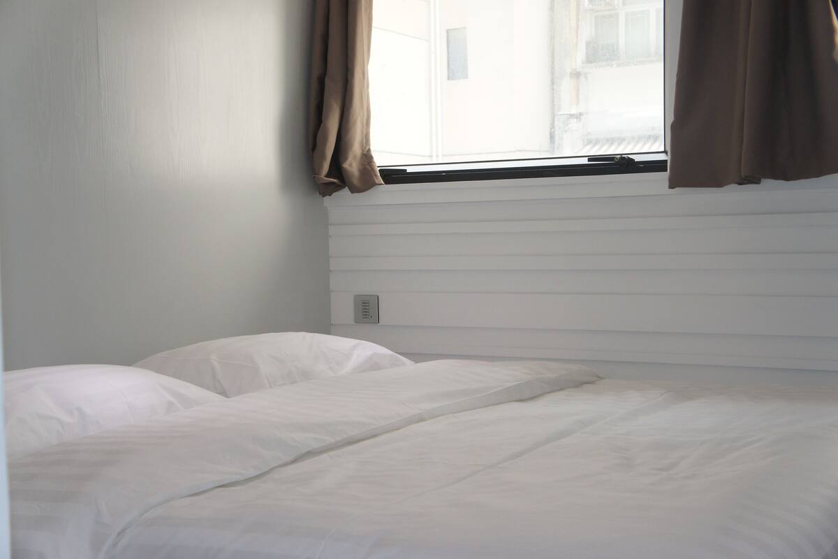 A room with a bed, a window with curtains, and a wall with horizontal lines.