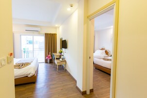 A hotel room with a bed, a desk, a chair, a TV, and a balcony with curtains.