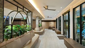 A modern hotel lobby with a long corridor, seating areas, and large windows. - Hi Chiangrai Hotel (Chiang Rai)