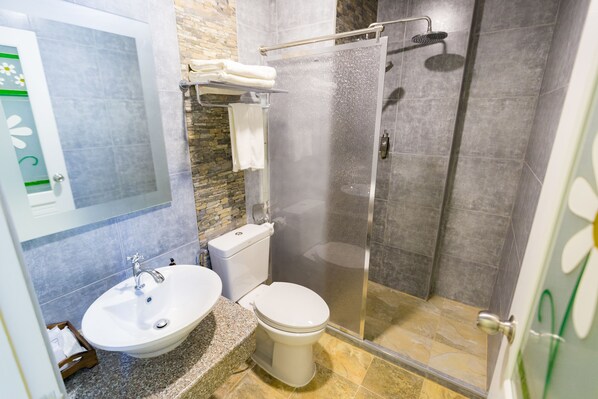 A bathroom with a sink, toilet, and glass shower enclosure.