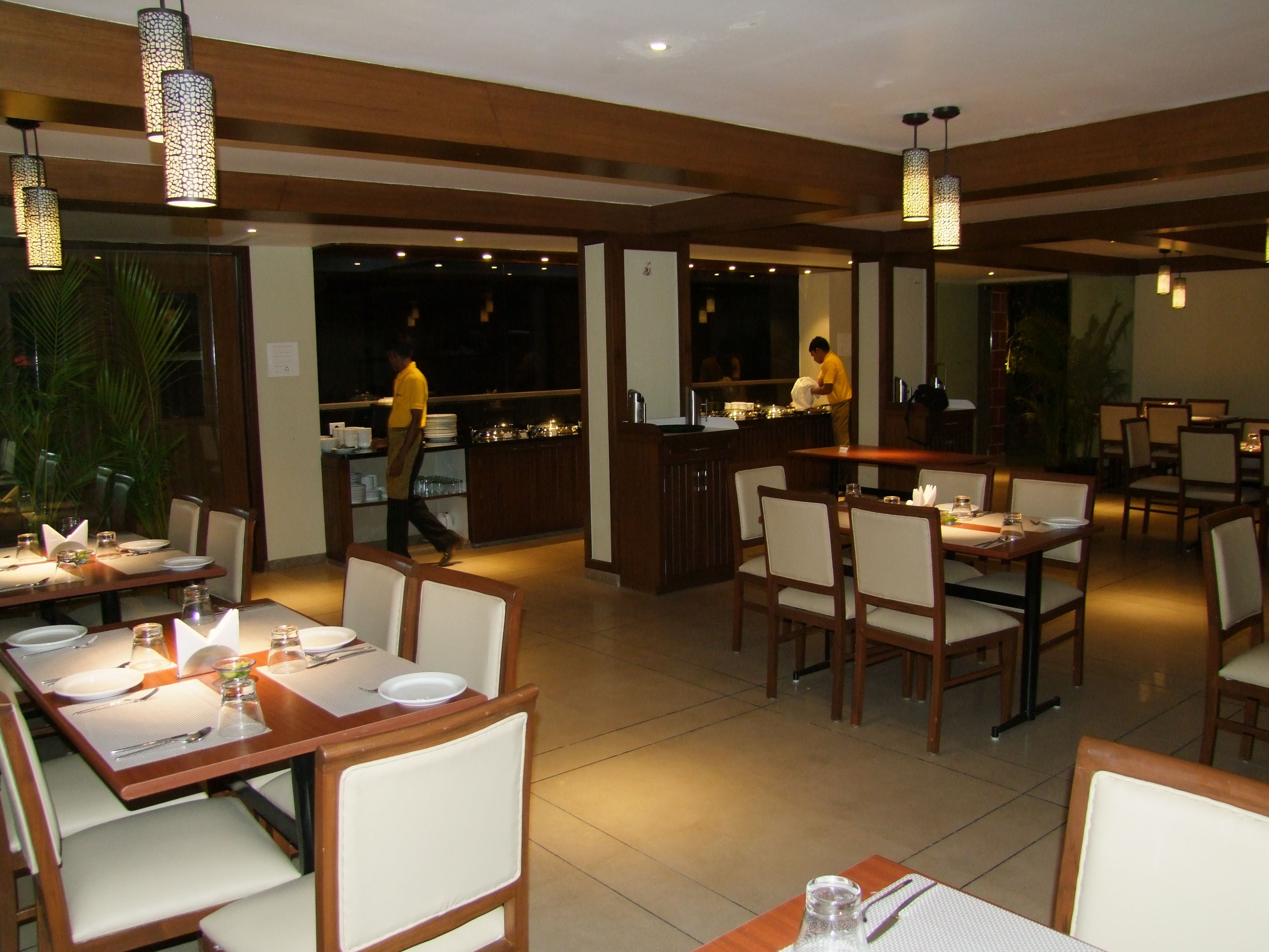 Un restaurante con varias mesas, sillas y lámparas colgantes.