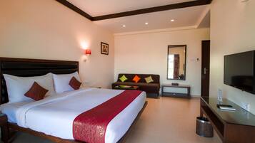 A hotel room with a large bed, a TV, a desk, and a sofa.