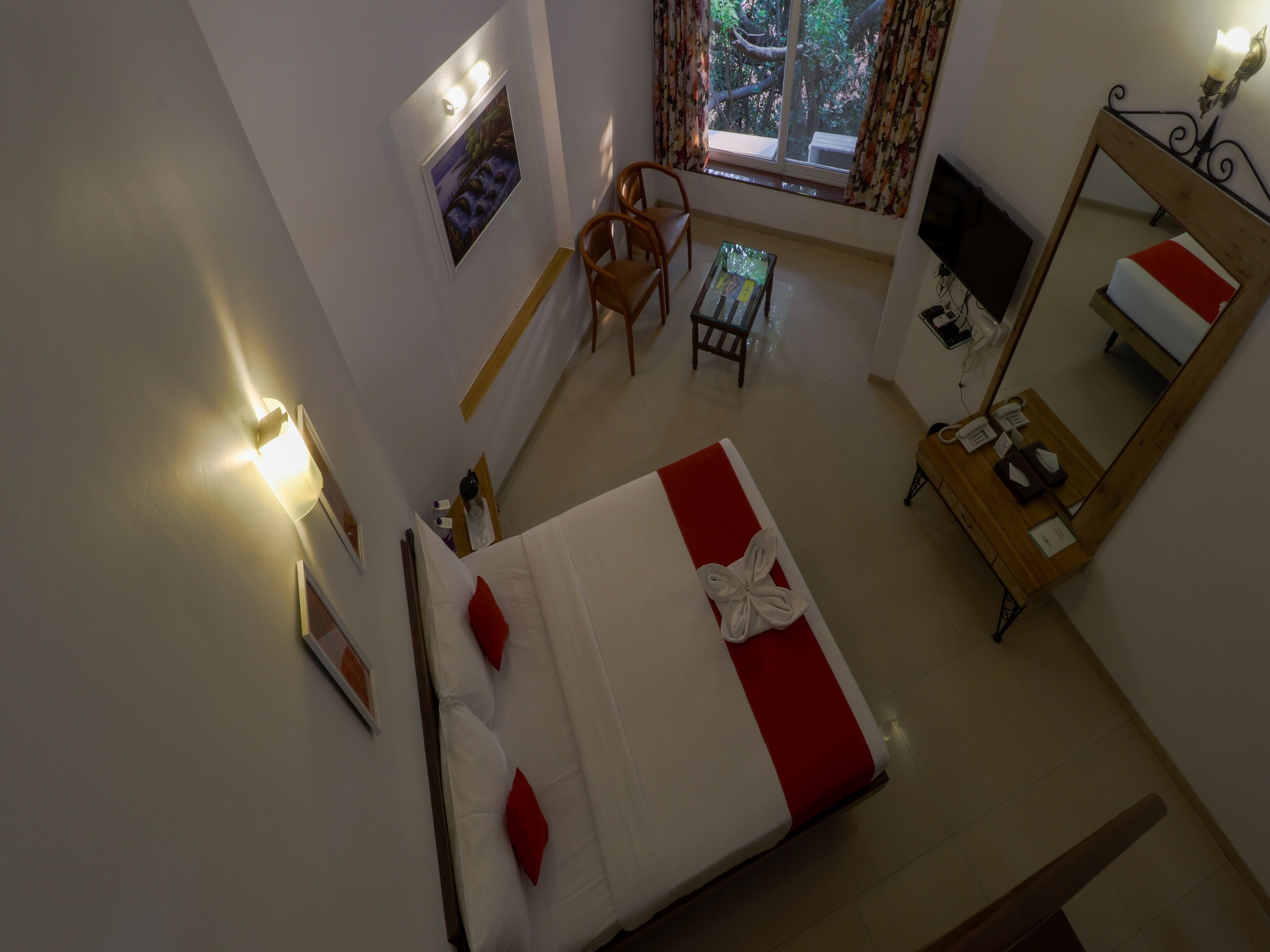 A hotel room with a bed, a desk, a chair, a TV, and a window with curtains.