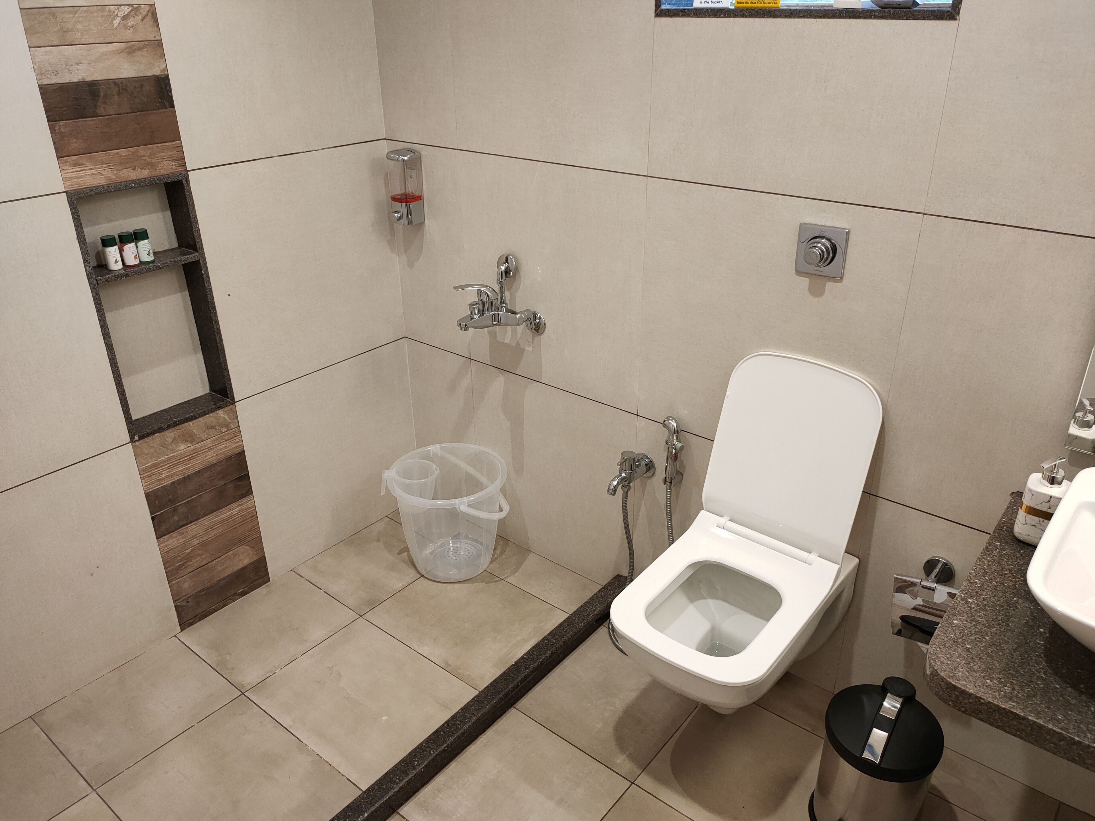A bathroom with a toilet, shower, and a shelf with toiletries.
