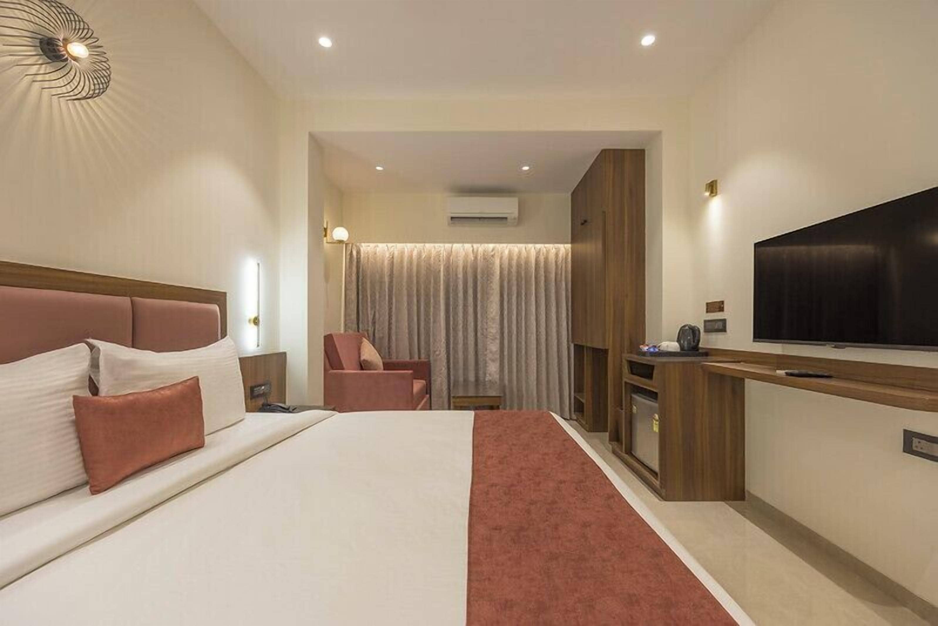 A hotel room with a large bed, a TV, a desk, and a chair.