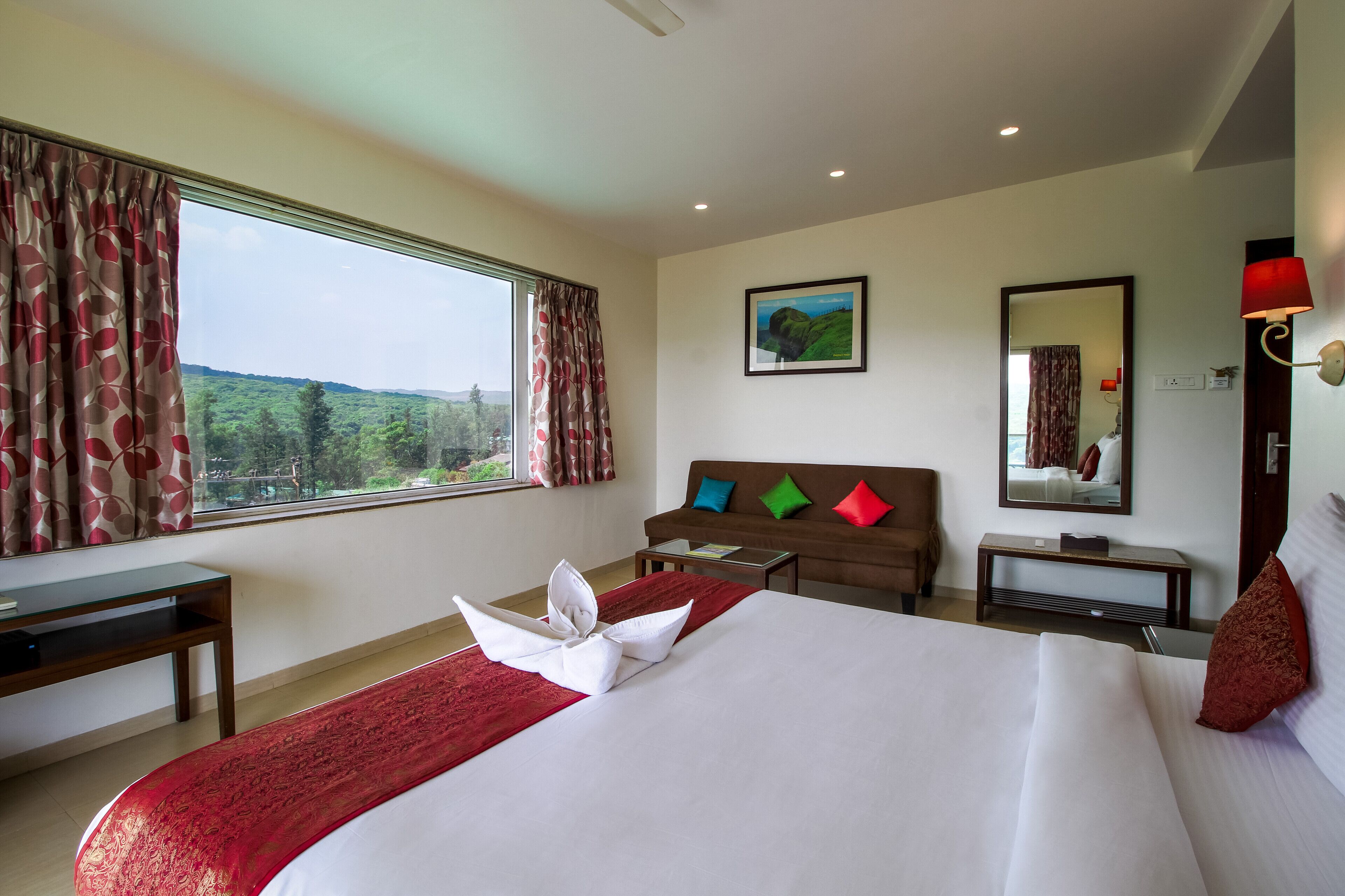 Habitación de hotel con una cama grande, un escritorio, un sofá y vistas a zonas verdes.