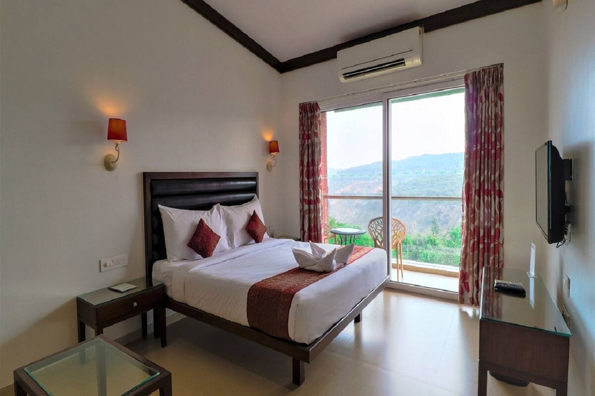 A hotel room with a large bed, a desk, a chair, and a TV.