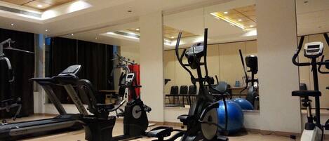 A gym with various exercise equipment including treadmills, elliptical machines, and stationary bikes.