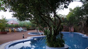 Una piscina al aire libre, sillones reclinables de piscina