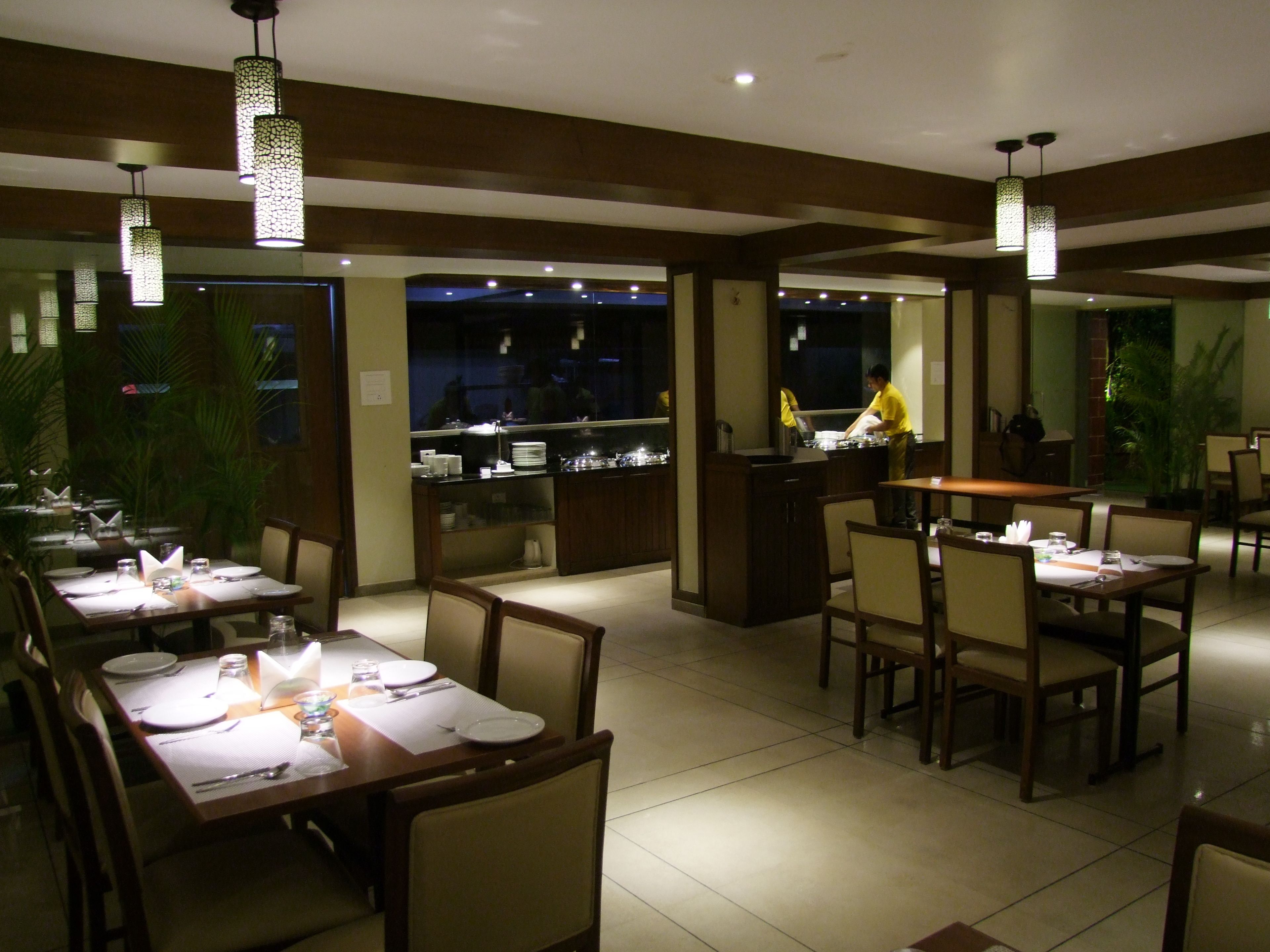 Un restaurante con varias mesas, sillas e iluminación colgante.