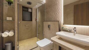 Een moderne badkamer met een douchecabine van glas, een wit toilet en een ruime wastafel met een spiegel erboven.