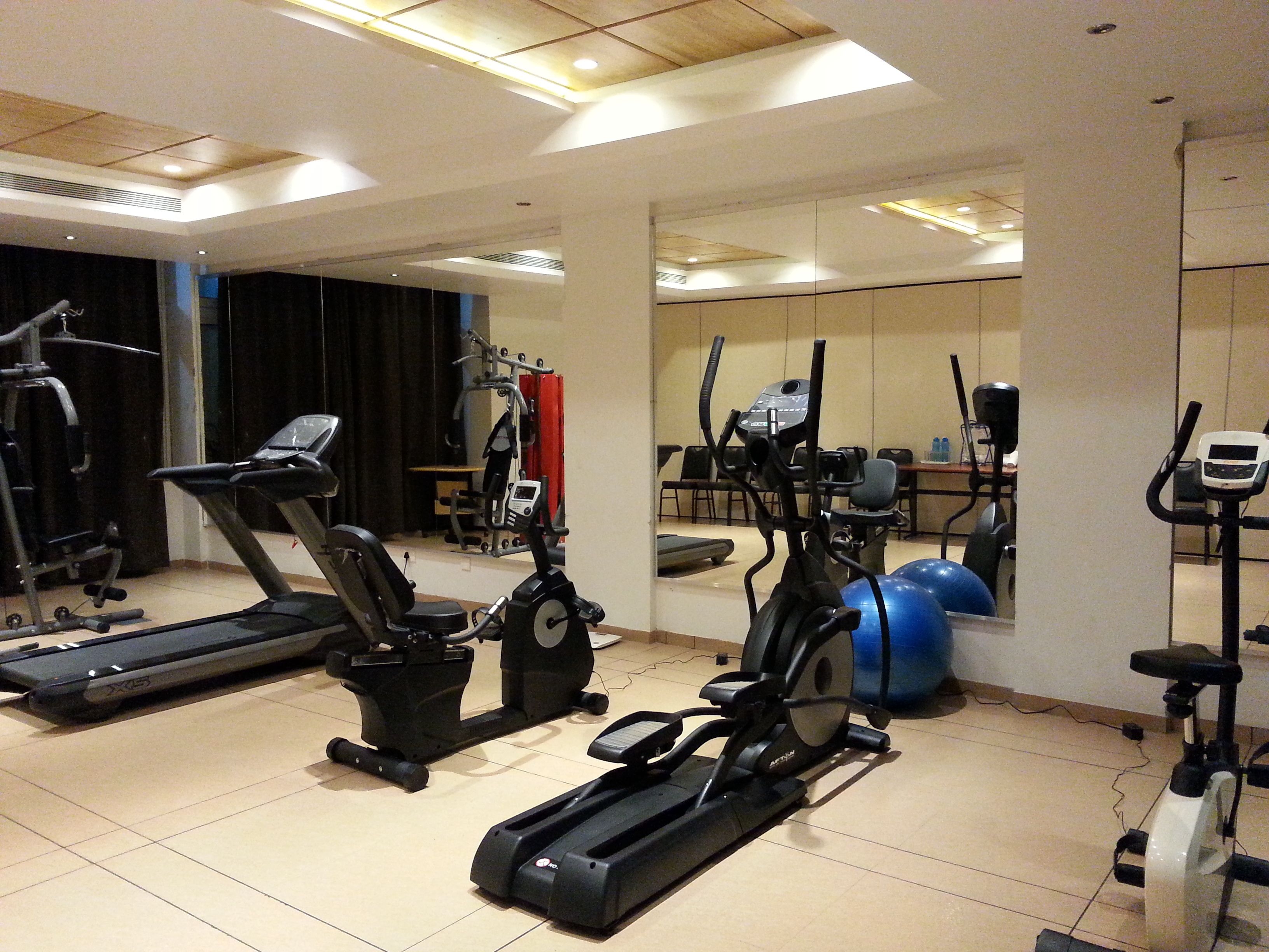 Un gimnasio con varias máquinas de cardio, incluyendo cintas de correr y elípticas, además de balones de ejercicio.