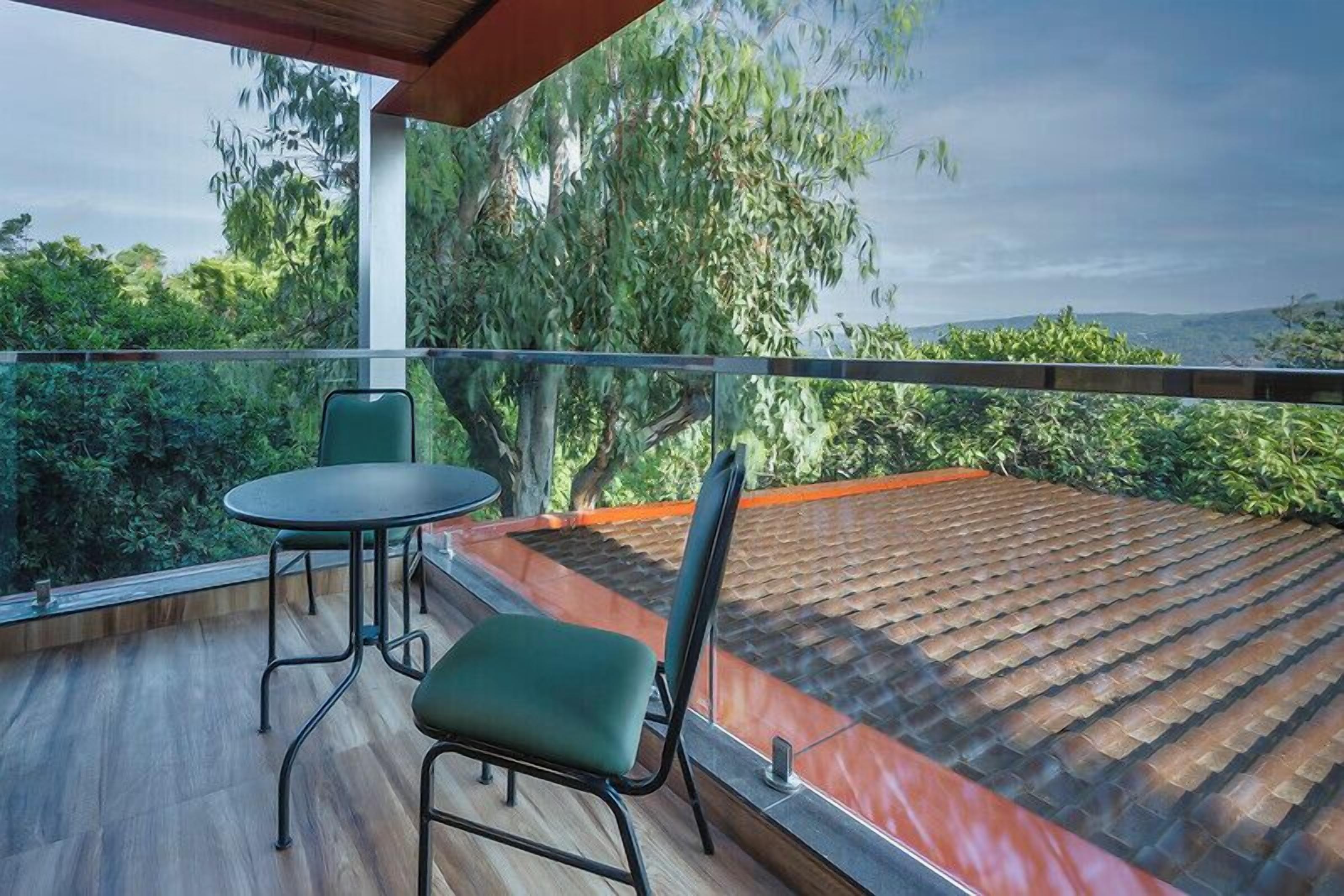 A balcony with a wooden floor, a table, and two chairs.