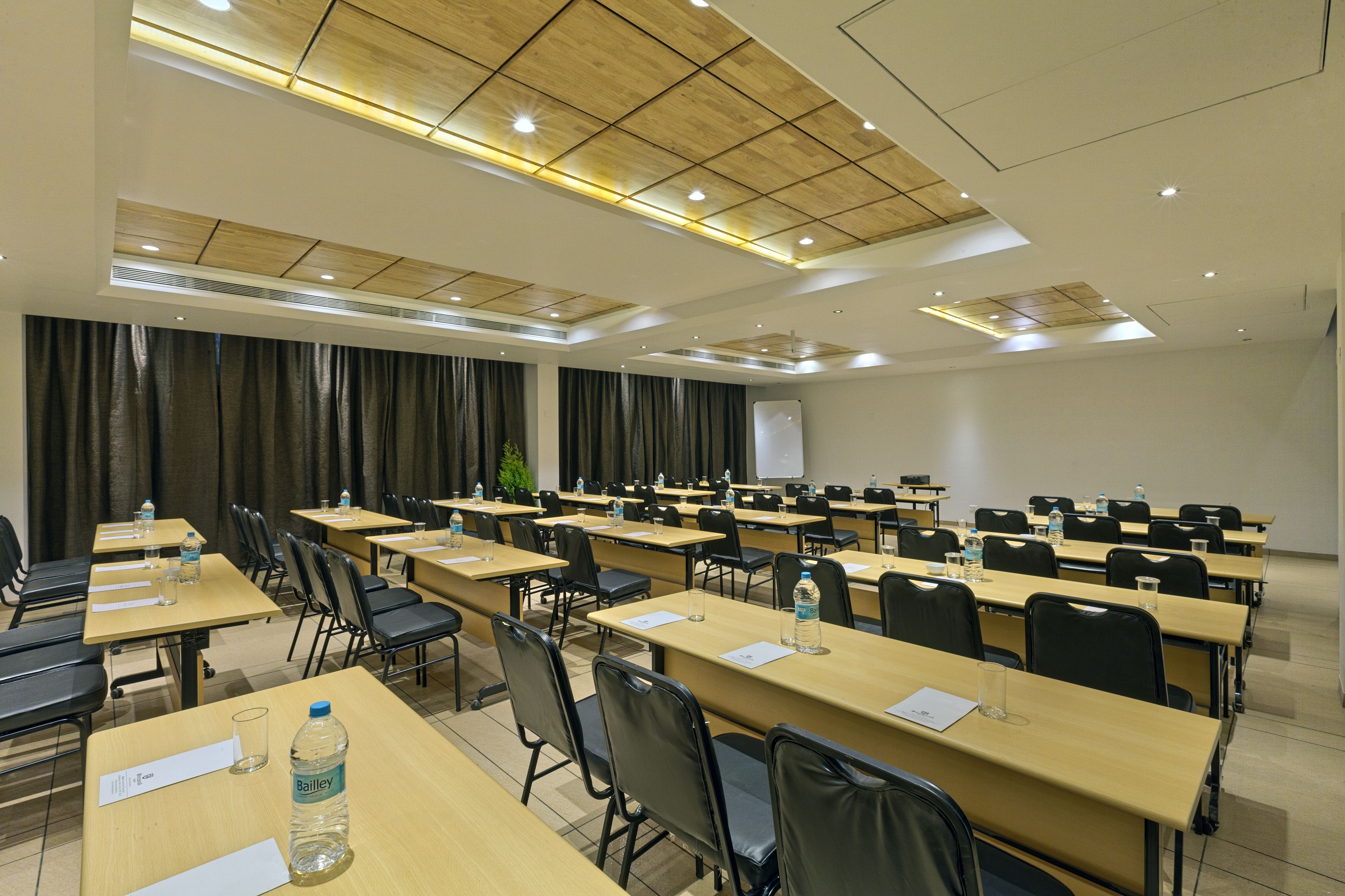 A conference room with multiple tables and chairs, equipped with water bottles and papers.