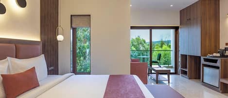 A modern hotel room with a large bed, a dining area, and a view of greenery.