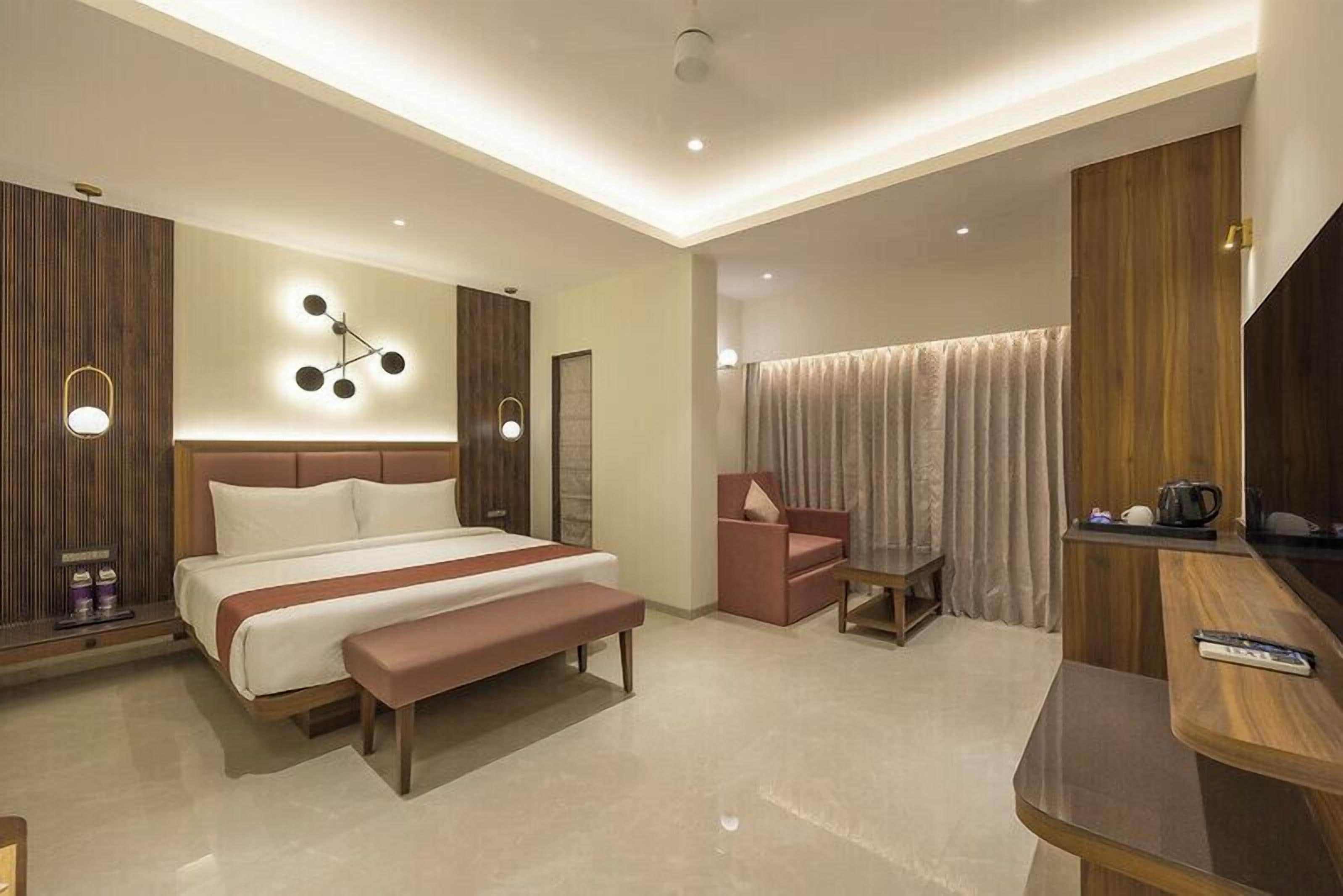 A modern hotel room with a large bed, a desk, a chair, and a TV.