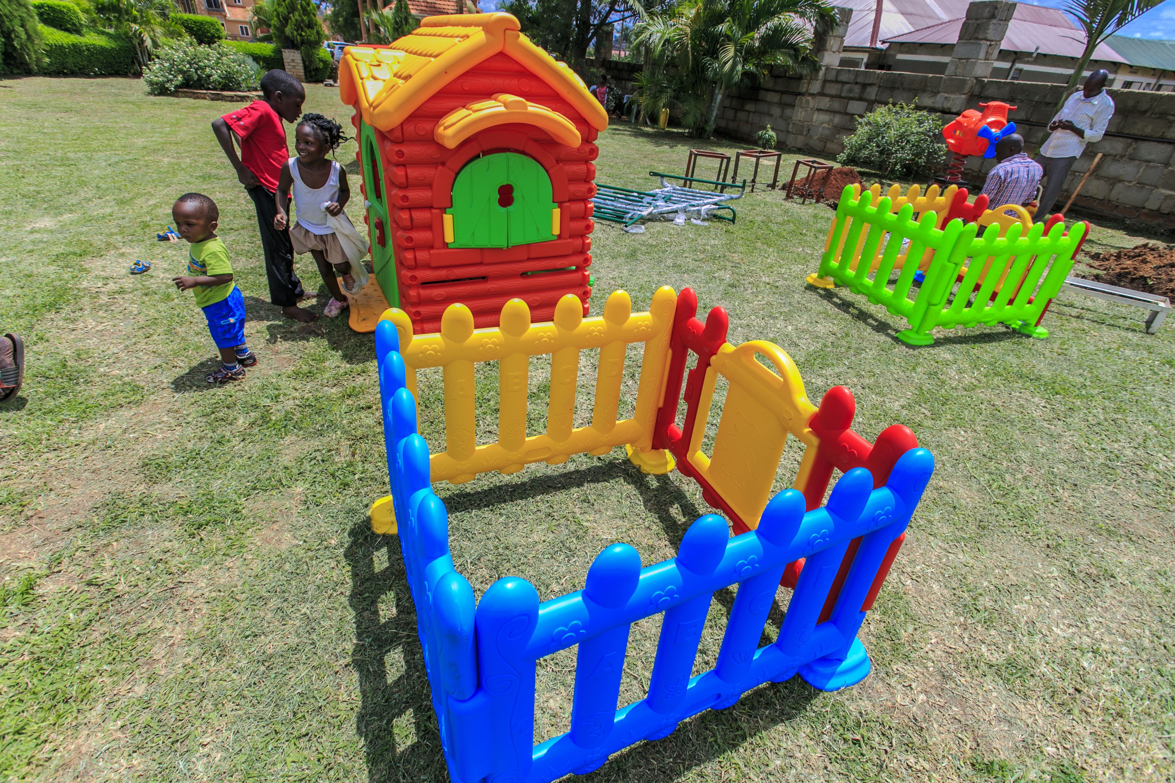 Un área de juegos infantiles con una casita y vallas de colores.
