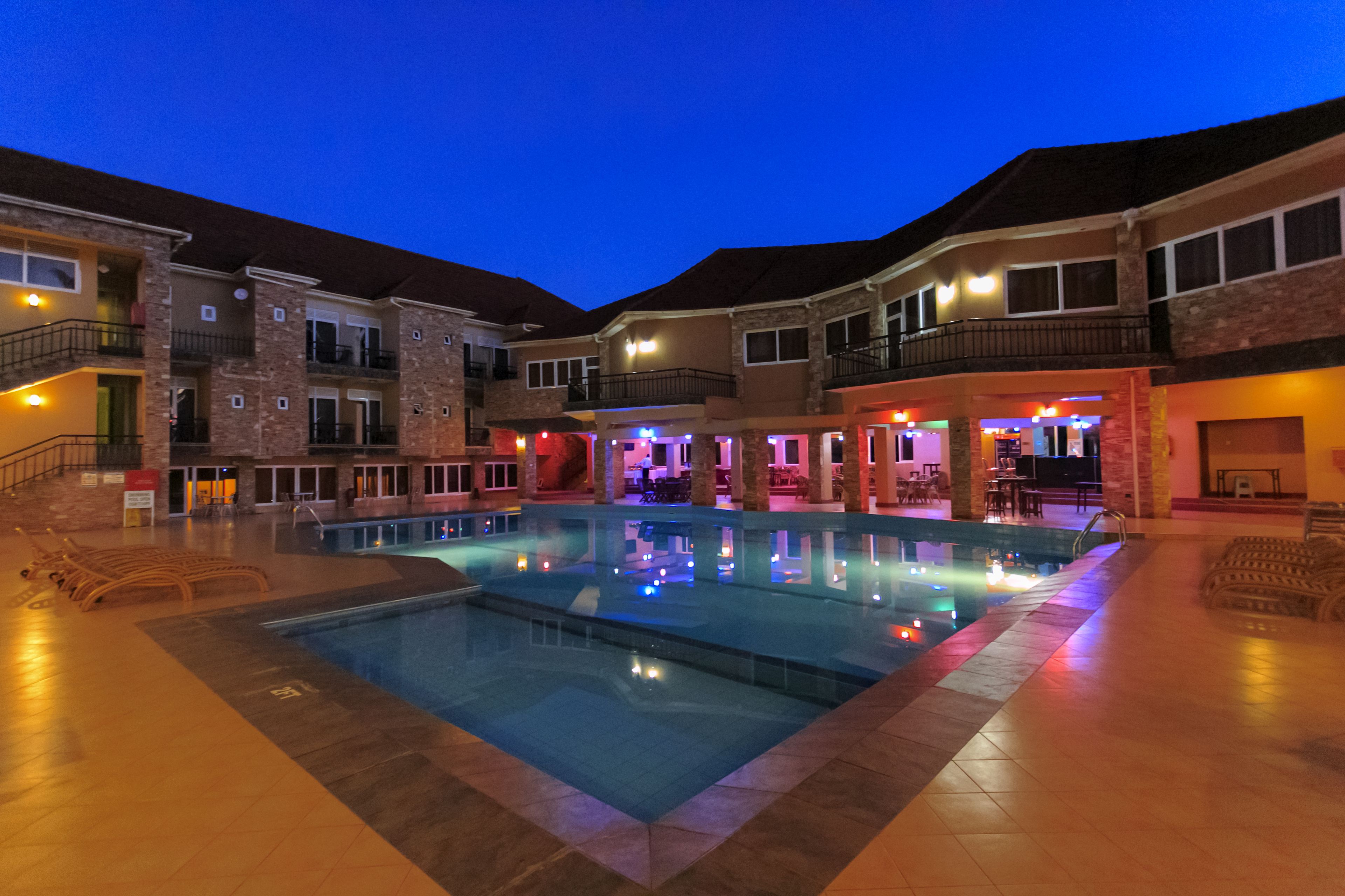 A hotel with a swimming pool, multiple balconies, and a well-lit outdoor area.