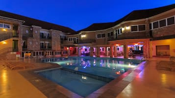 Ein Hotel mit Schwimmbad, mehreren Balkonen und einem gut beleuchteten Außenbereich.