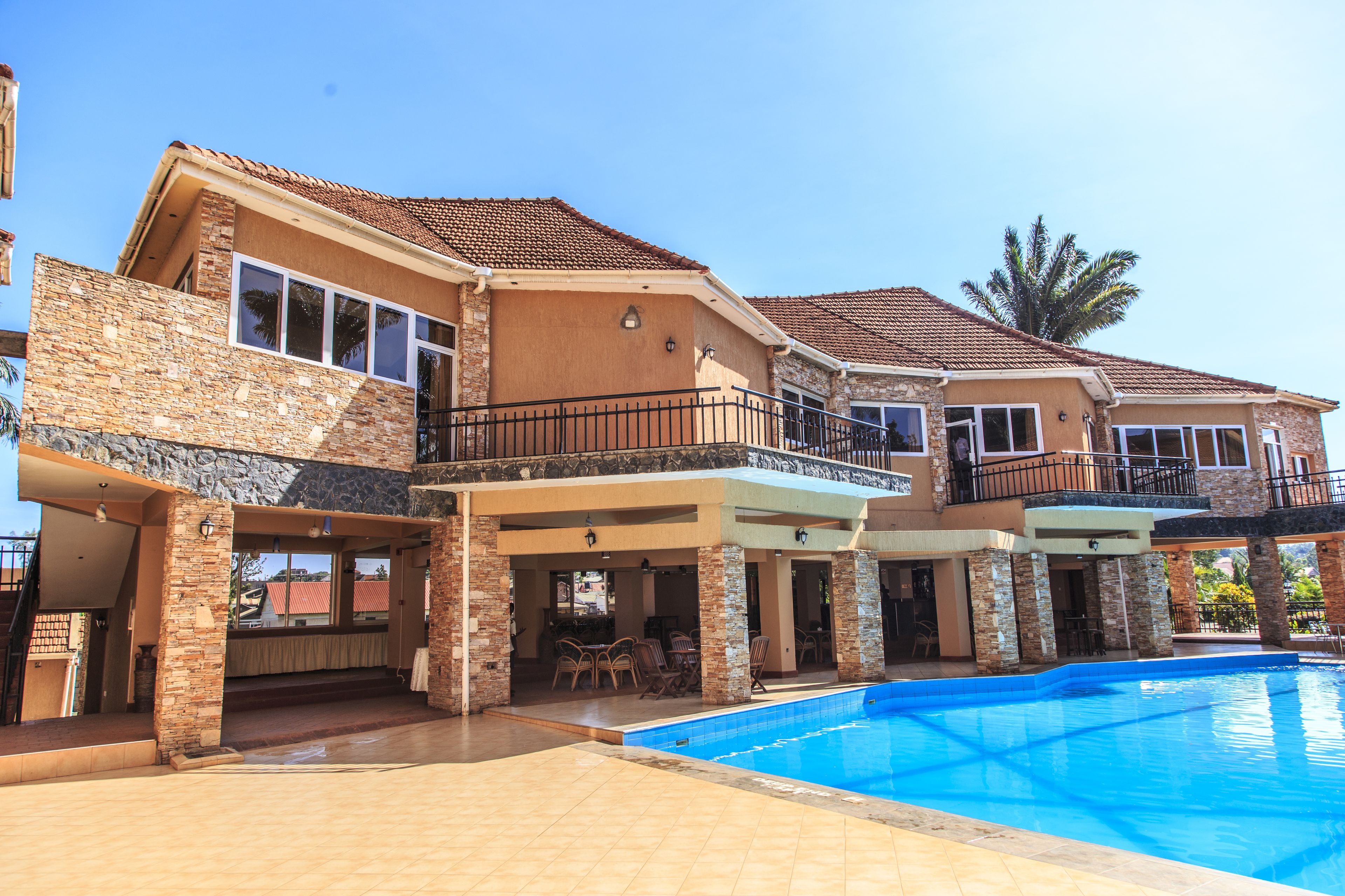 A multi-story house with a swimming pool, stone and stucco exterior, and outdoor seating area.