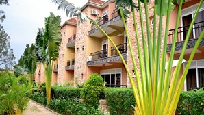 A multi-story hotel with balconies, surrounded by lush greenery and a paved pathway. - Wash and Wills Hotel (Mbale)