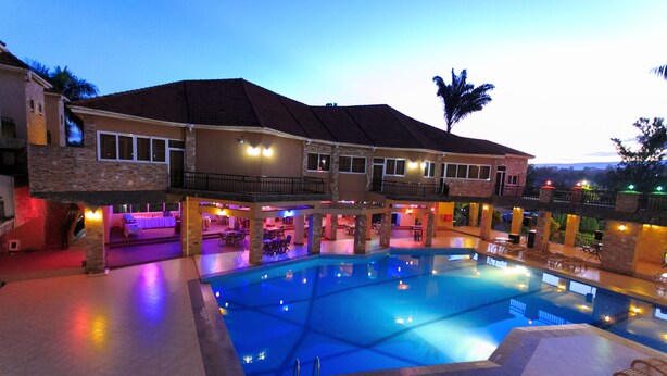A hotel with a large indoor swimming pool, multiple balconies, and a well-lit outdoor area. - Wash and Wills Hotel (Mbale)