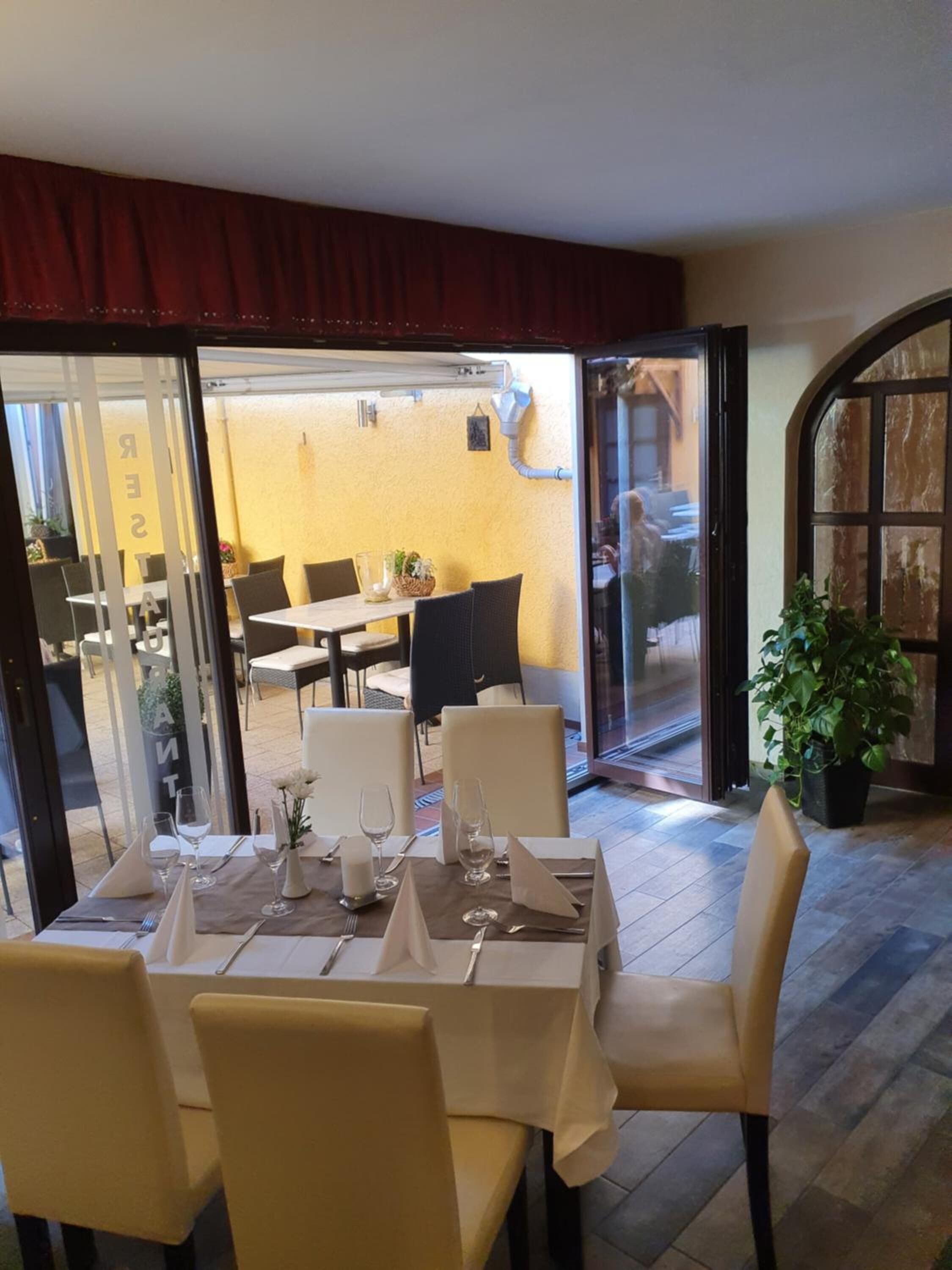 A dining area with a table set for four, chairs, and a potted plant.