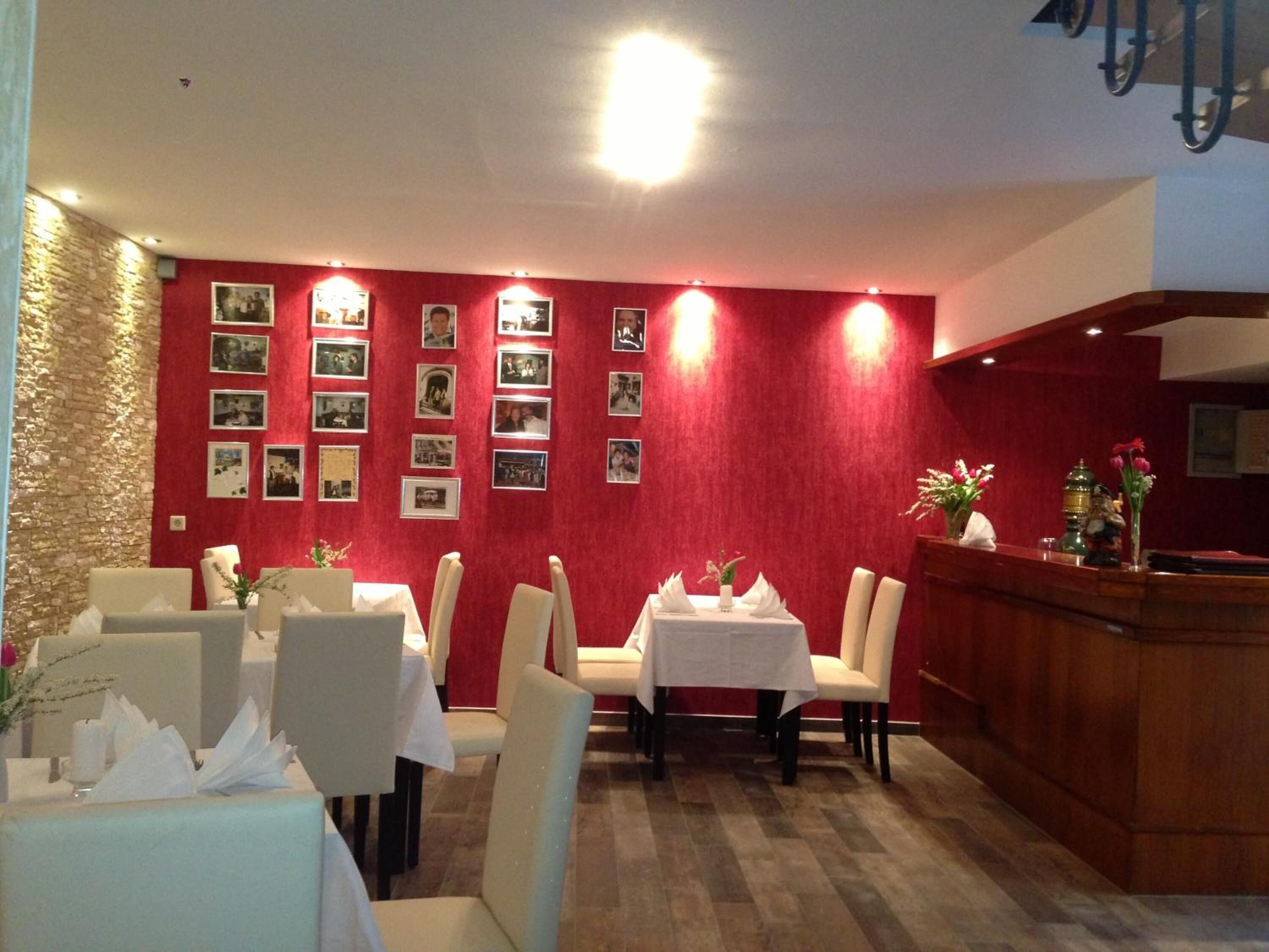 A restaurant with red walls, multiple tables, and chairs.
