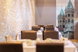 Un restaurante con mesas preparadas para comer, una pared de ladrillo y un mural de un edificio histórico.