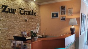 A reception desk with a stone facade, a sign reading "Zur Grube", and a few framed pictures on the wall. - Hotel Restaurant Zur Traube (Freyburg)