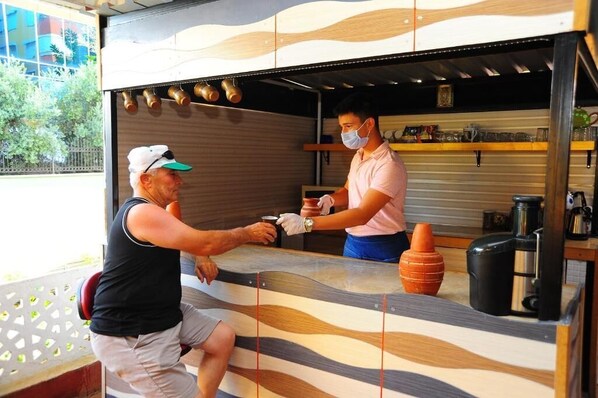 A counter with a modern design, a person wearing a cap and a tank top, and another person in a pink shirt.