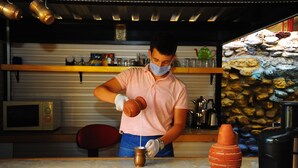 A person pouring a liquid from a jug into a pot. There is a microwave, a red chair, and a stone wall in the background. - Best Life Apart Hotel (Alanya)